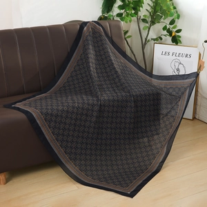 Elegant black chiffon headscarf with floral print draped over a leather sofa