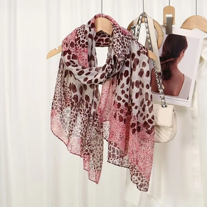 Detail of pink leopard print scarf displayed on a wooden hanger with fashion accessories
