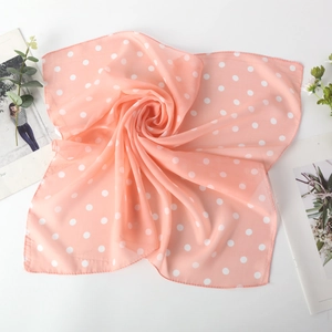 Carré de soie en mousseline rose pêche à pois présenté dans un élégant tourbillon