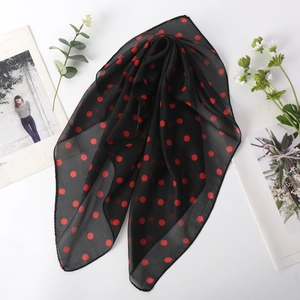 Détail d'un foulard léger en mousseline noire avec un motif à grands pois rouges vifs