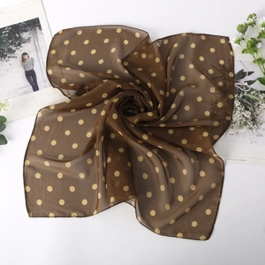 Détail macro d'un foulard en mousseline marron à pois montrant sa texture soyeuse