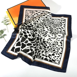 Detail of silk-like leopard print scarf featuring navy blue borders and satin finish
