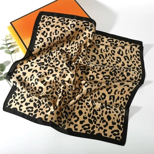 Detail of leopard print silk scarf draped over gift boxes with smooth satin texture