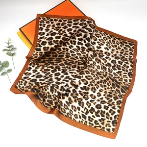 Close-up of leopard print silk scarf with brown edges and elegant satin finish texture