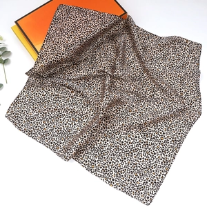 Close-up of leopard print silk scarf texture and fine hem with colorful box packaging