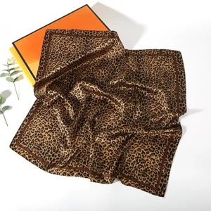 Close-up of leopard print satin scarf texture with elegant draping on gift boxes