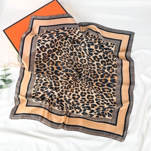 Detailed view of luxury leopard print silk square scarf on white fabric with gift box