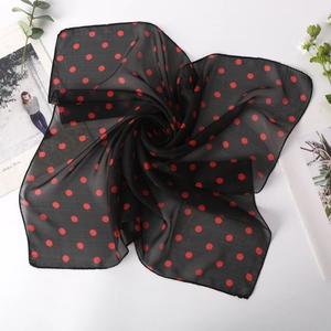Écharpe carrée en mousseline noire à pois rouges pliée en spirale sur fond blanc