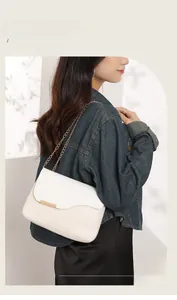 Detail of white patchwork woven bag with gold chain strap and elegant metallic trim