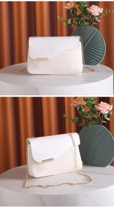Detail of white woven crossbody bag with gold chain strap and metallic hardware