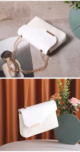 Detail of white woven crossbody bag with asymmetric leather flap and gold chain strap
