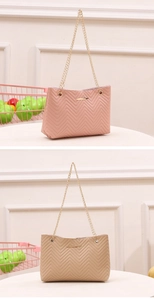 Detail of pink and khaki quilted handbags with golden metal chain straps on white stand