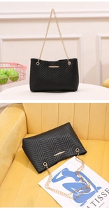 Detailed close-up of a black V-quilted faux leather handbag with elegant gold chain straps