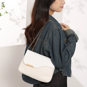 Fashionable woven crossbody bag with gold chain and contrasting white leather flap