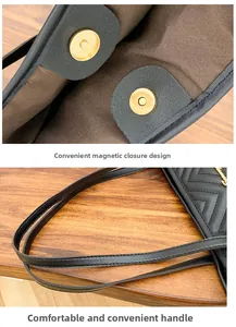 Dettaglio della borsa tote nera con chiusura magnetica e manici morbidi su legno