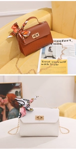 Detail of woven texture handbag with golden square lock and decorative silk scarf