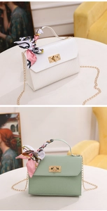 Detail of elegant handbags with woven texture, decorative silk scarf, and gold chain straps