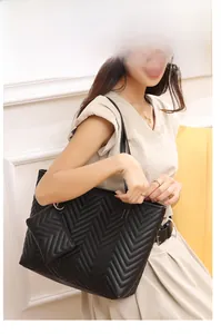 Dettaglio della borsa tote nera trapuntata a V con logo dorato e pochette coordinata