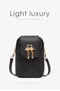 Detail of black quilted crossbody bag with golden swan heart charm and chain tassel