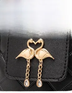 Detail of black pebbled leather bag featuring V-shaped stitching and golden flamingo clasp