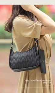 Close-up of black quilted shoulder bag with matching mini pouch and gold hardware details