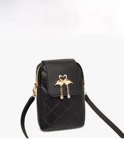 Detail of black quilted crossbody phone bag with golden flamingo clasp and tassel charm