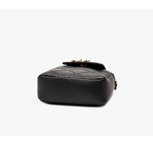 Detail view of black quilted crossbody bag with gold hardware and pebbled leather texture