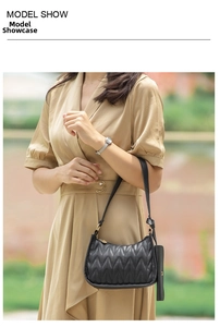Close-up of black quilted hobo bag with chevron pattern and mini pouch on beige dress