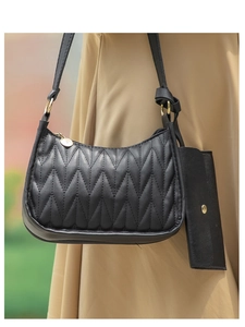 Close-up of black quilted hobo bag with V-shaped stitching and small hanging pouch