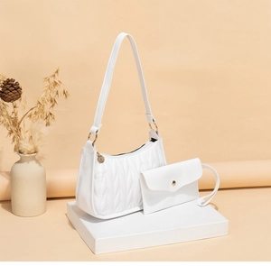 Close-up of white quilted underarm bag set with gold hardware on a display stand