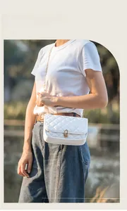 Detail of white quilted crossbody bag with golden chain strap and metallic lock