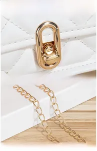 Macro detail of polished gold-tone clasp and chain on quilted white leather bag