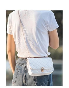 Detailed view of white quilted chain bag with gold twist lock on a crossbody model