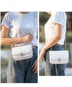Detail of white quilted crossbody bag with golden chain strap and metal lock closure
