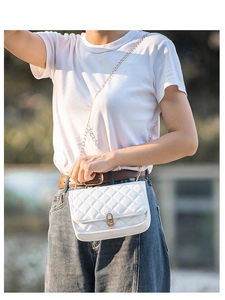 Quilted white crossbody bag with gold chain strap shown on model in outdoor natural light
