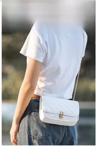 Close-up of a white quilted chain bag featuring a gold rotary lock and leather strap