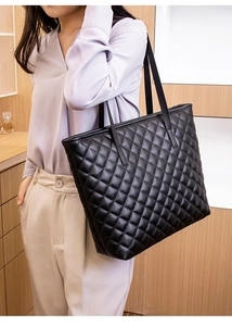 Close-up of black quilted leather texture and fine stitching on high-capacity tote bag
