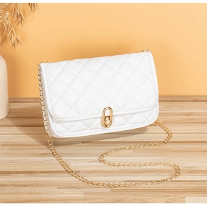 Close-up of white quilted crossbody bag with golden twist lock on wooden surface