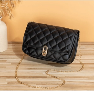 Close-up of black quilted PU leather crossbody bag with golden rotary lock and chain strap