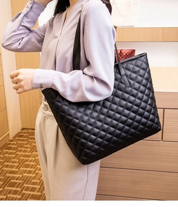 Close-up of quilted black tote bag styled with a lavender shirt and white trousers