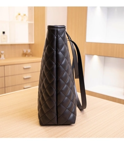 Side view of black quilted leather tote bag showcasing the diamond stitched pattern