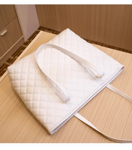 Close-up of white quilted tote bag featuring elegant diamond lattice stitching and leather texture