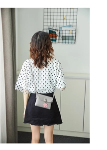 Gray leather mini crossbody bag with a pink star pendant shown worn on a female model