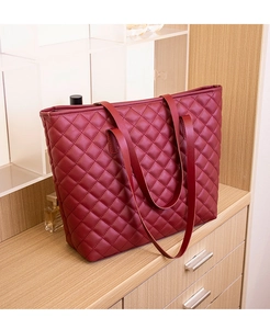 Detailed view of wine red quilted tote bag with diamond stitching on a wooden surface