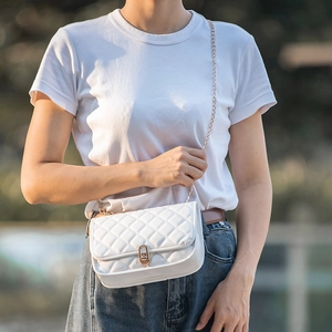 Quilted white crossbody bag with gold chain strap and oval twist lock on female model