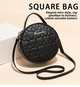 Detailed view of black round crossbody bag with heart quilted pattern and gold hardware