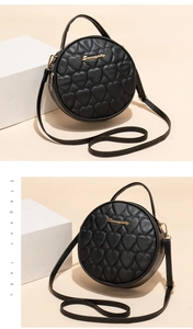 Detail of black round crossbody bag with heart quilting and elegant gold lettering