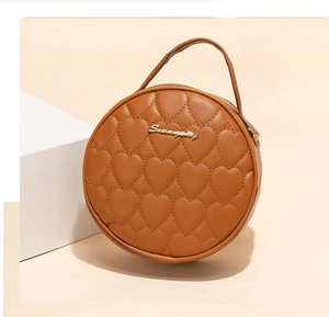 Detail of round caramel leather handbag featuring heart-shaped quilted stitching and gold logo