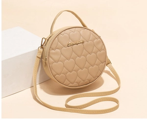 Detail of round beige crossbody bag with heart quilting and metallic logo accent