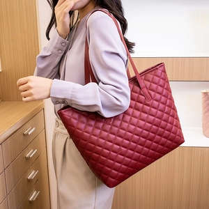 Burgundy quilted tote bag with large capacity, shown on a model in a warm interior setting